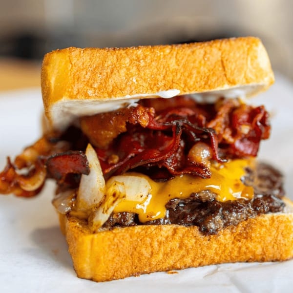 Busloop Burgers' bacon cheeseburger with grilled onions on toasted bread.